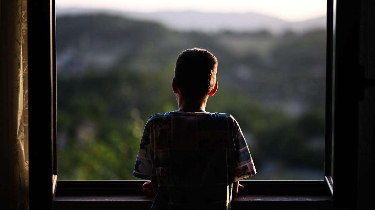 Un niño mira por una ventana.