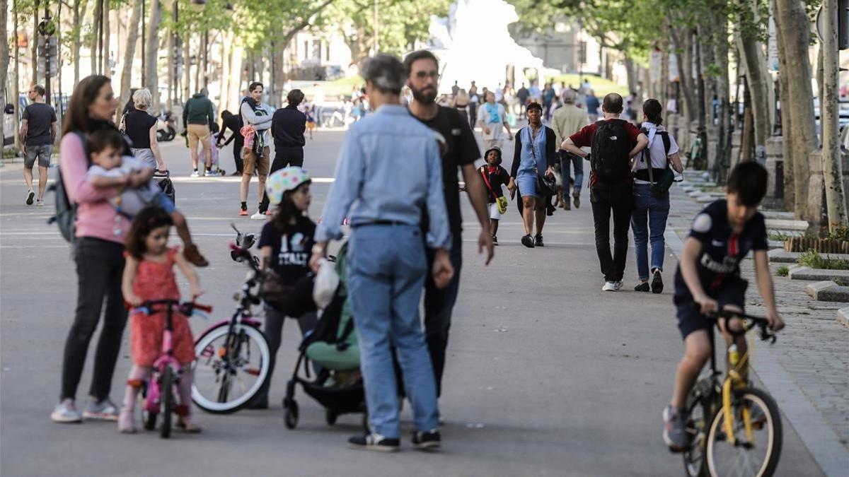 Padres pasean por sus hijos por una calle peatonal de París, este domingo.