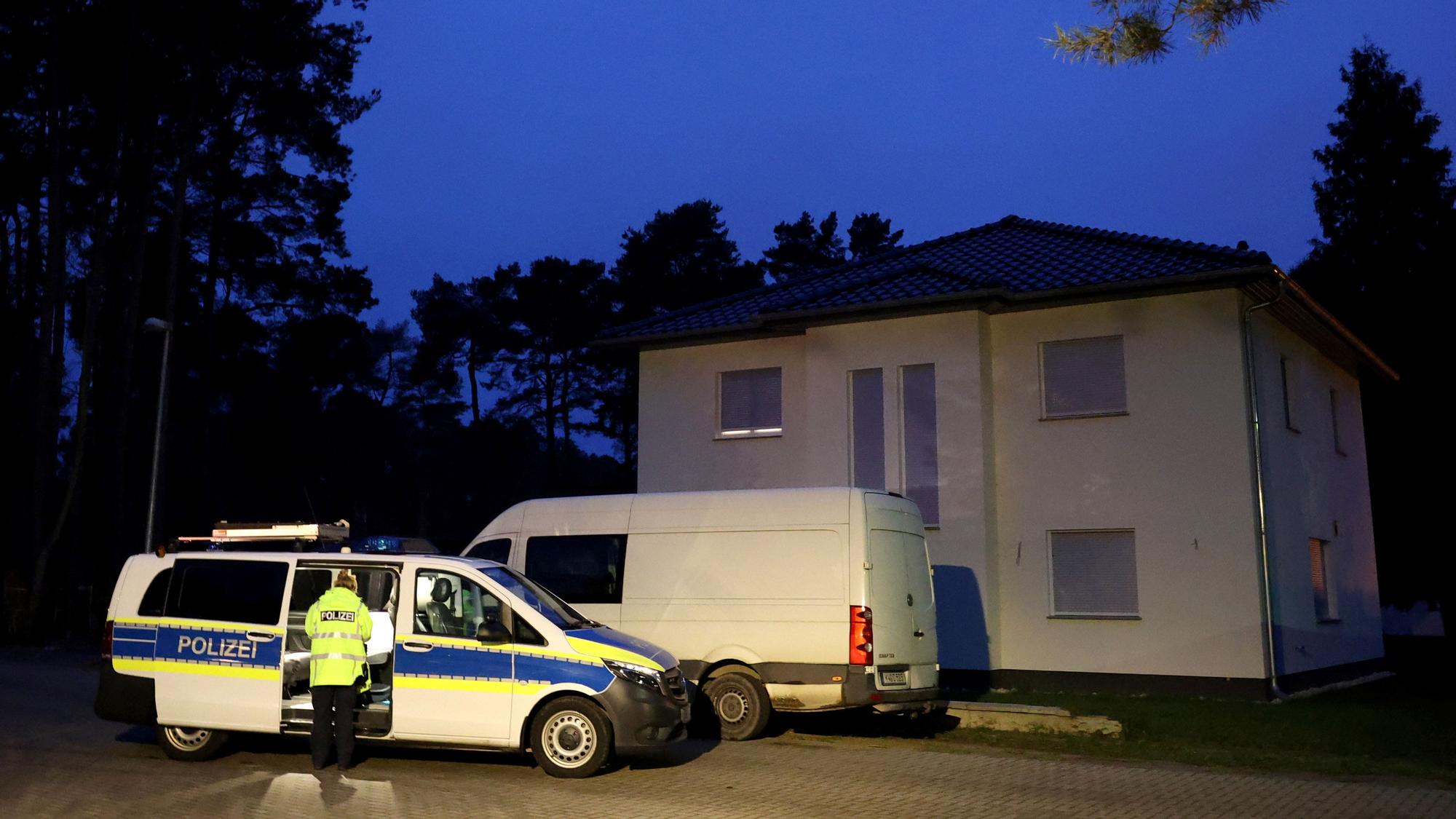 A police vehicle is parked in front of a family home after German police found two adults and three children shot or stabbed to death in Senzig, a town south of Berlin, Germany, December 4, 2021. They found two adults, both 40, and children aged four, eight and 10, dead from gunshot and stab wounds. REUTERS/Christian Mang