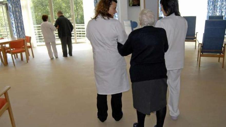 Varias cuidadoras atienden a dos mayores en una residencia. / bernabe / luismy