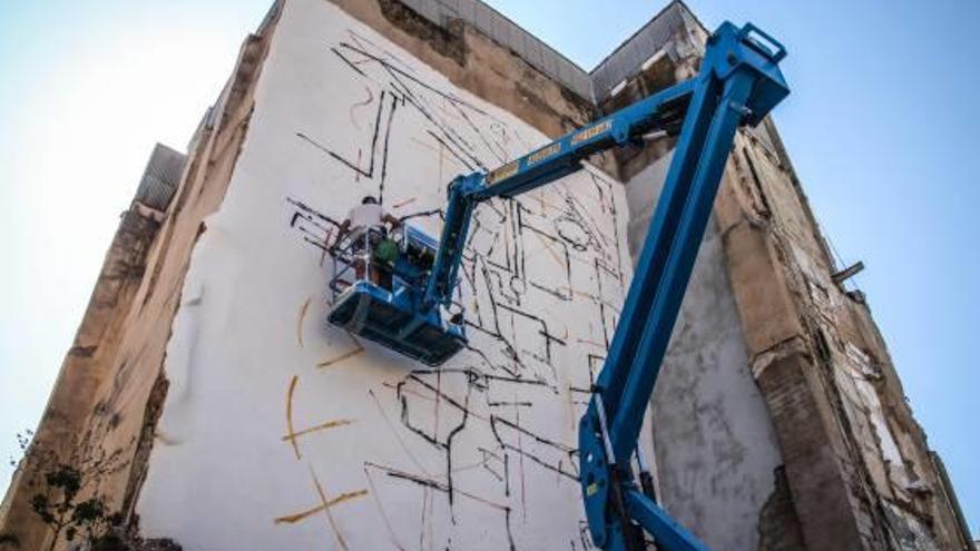 Dos de los artistas que participan pintando un mural en la calle Verge María de Alcoy.