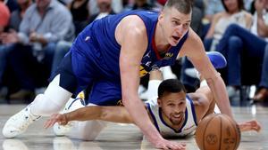 Jokic y Curry pelean, en el suelo, por el control de un balón en el tercer partido