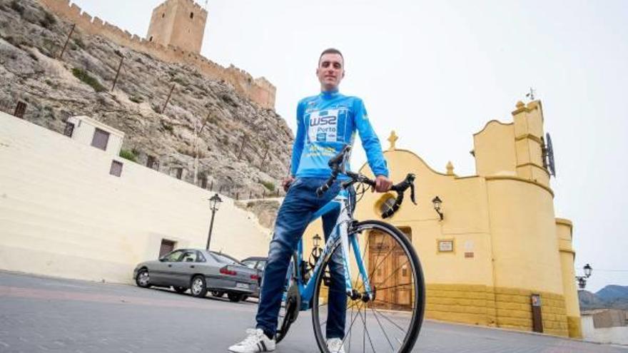 Raúl Alarcón, en la plaza de San Blas de Sax, con el maillot de ganador de la Vuelta a Asturias y el castillo detrás.