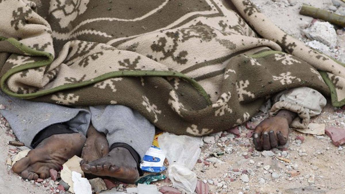 Un cadáver en descomposición, cubierto por una manta, en una calle de Sirte, el domingo.