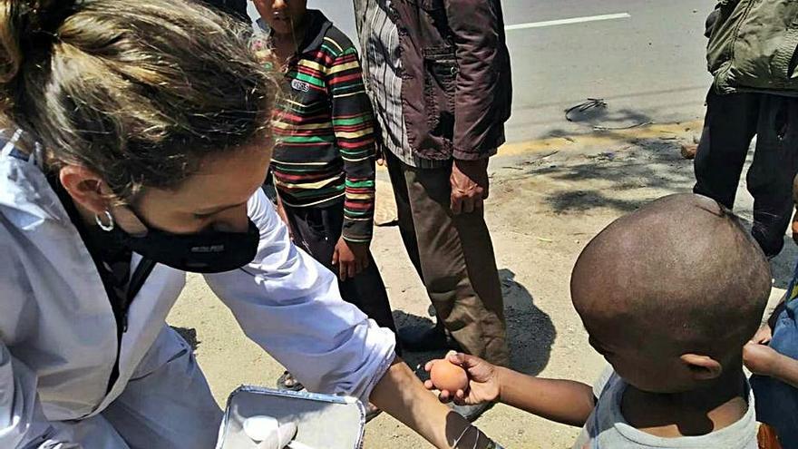 Vives entrega una ración de comida a un niño. | 
