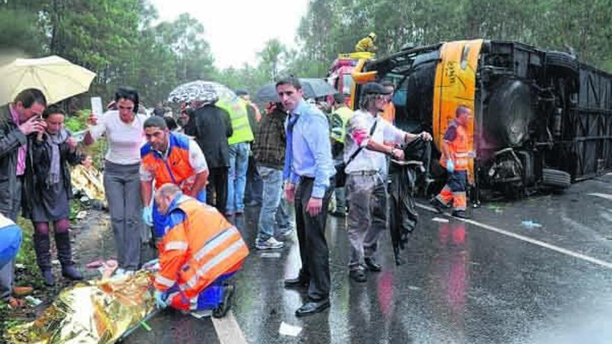 Uno de los heridos es trasladado en una camilla a la ambulancia junto al autobús volcado.  // Noé Parga