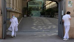 Dos trabajadores del Hospital Clínic de Barcelona, a las puertas del centro, este jueves.