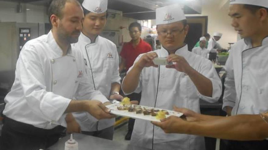 Montagudo trabaja en un plato bajo la atenta mirada de parte del personal de su cocina.