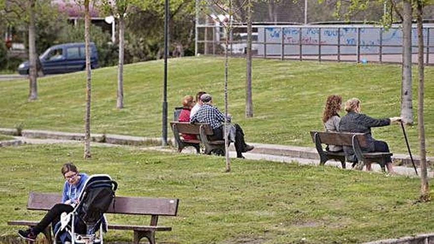 Una madre con su hijo y jubilados en bancos de un parque.