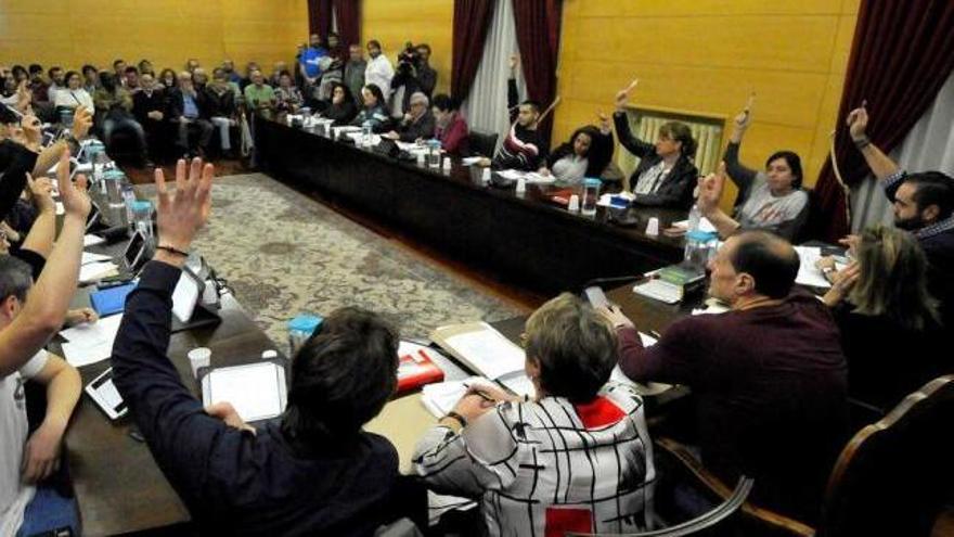 Los concejales de IU y Somos levantan la mano durante un Pleno en el Ayuntamiento de Langreo.