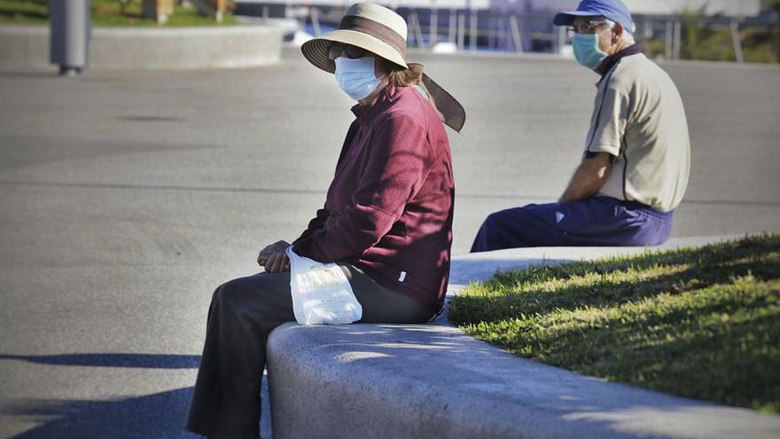 Dos personas mayores descansan manteniendo la distancia de seguridad y con sus mascarillas en Santa Cruz.