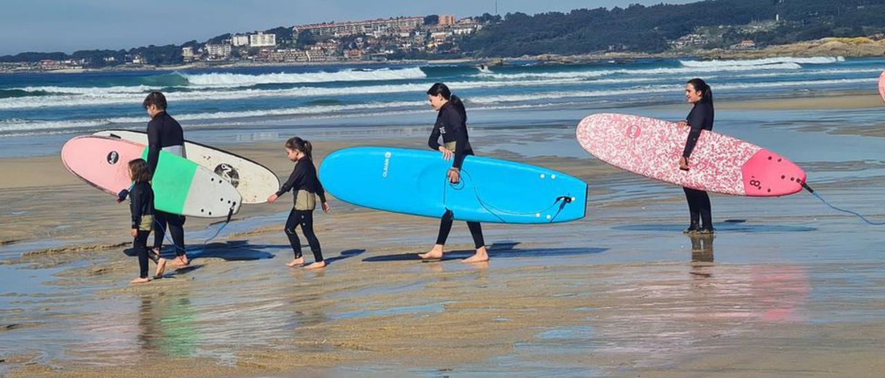 Alumnos y monitores del Grove Surf Club, que 
cumple diez años, a punto de entrar al agua.   | // M. MÉNDEZ