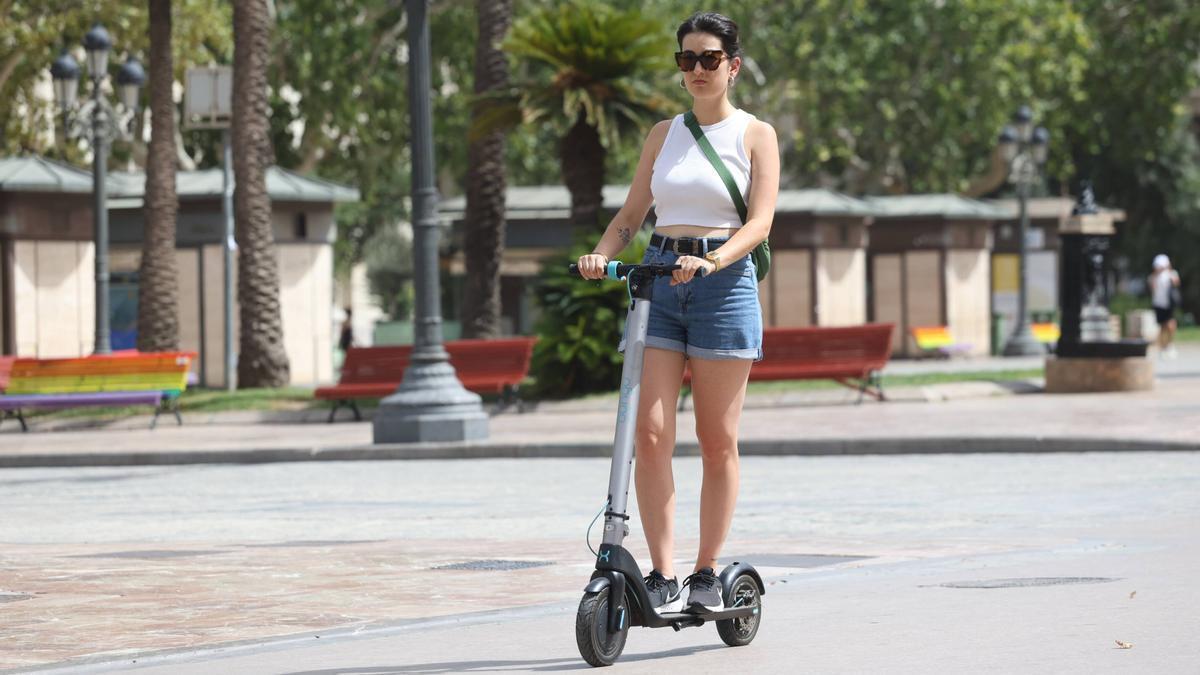 Una usuaria de patinete eléctrico circula sin casco en la Plaza del Ayuntamiento de Valencia.