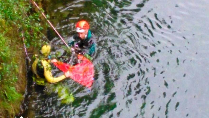 Un bombero y un guardia civil, en la operación de extracción del cadáver del río.