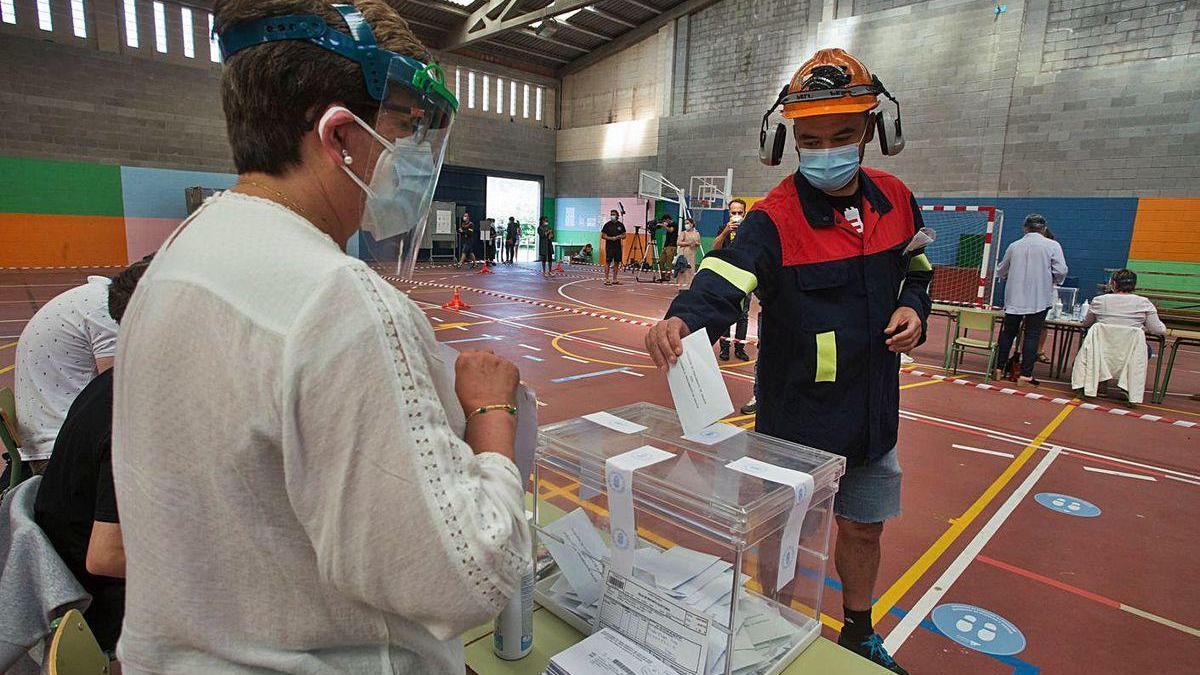 Un trabajador de Alcoa vota ataviado con el uniforme en un pabellón en Burela.