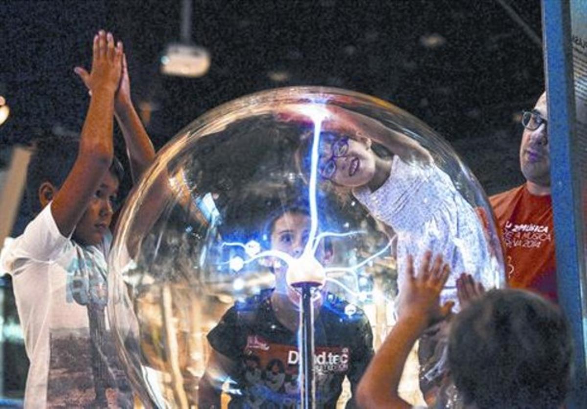 Uns nens experimenten ambla bola de plasma a la zona interactiva de CosmoCaixa.