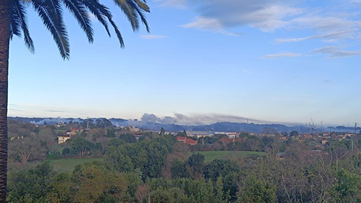 Al fondo, humareda procedente de la zona industrial, sobre el oeste de Gijón, en una imagen tomada en la mañana de este sábado desde La Pedrera