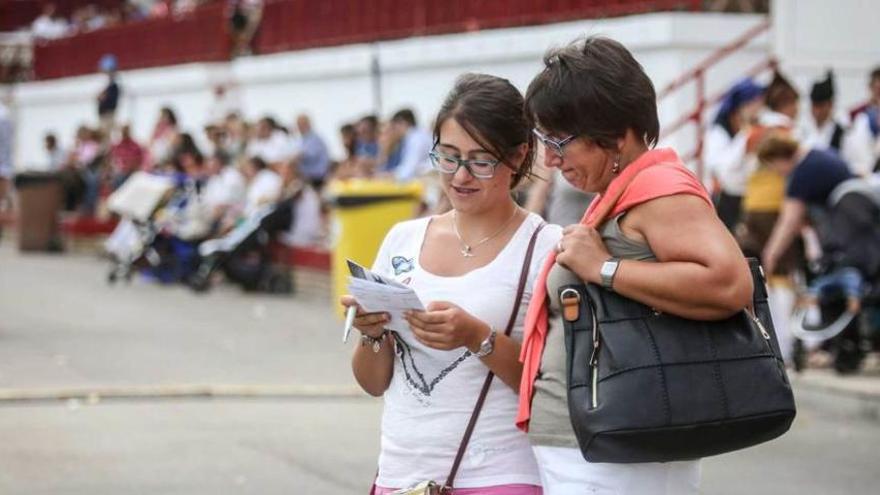 Dos aficionadas consultan el programa.