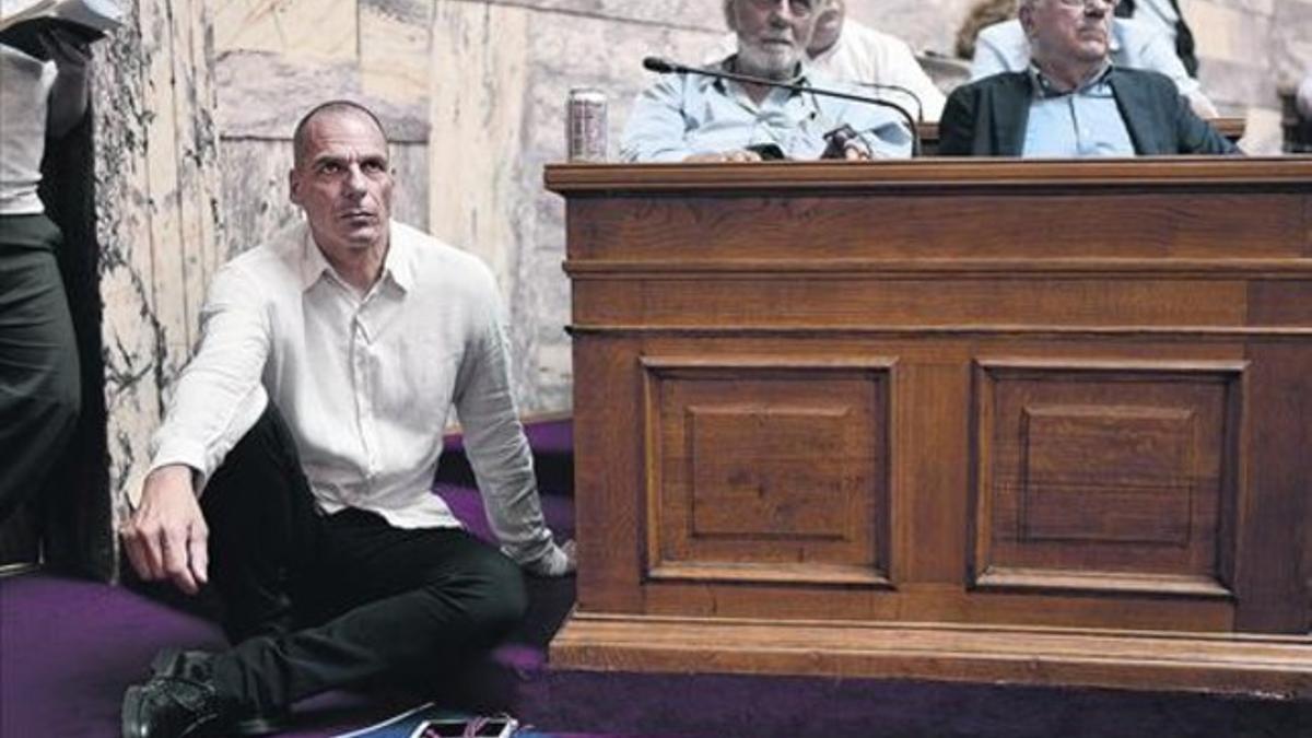 El ministro de Finanzas, Yanis Varoufakis, escucha sentado en el suelo la intervención del primer ministro griego en el Parlamento de Atenas, ayer.