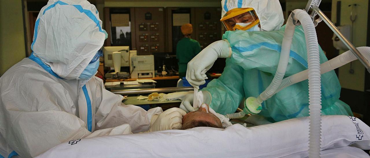 Dos profesionales atienden a un enfermo en la unidad de críticos del Hospital Montecelo. |   // POOL RAMÓN LEIRO