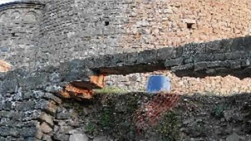 Tram del mur de contenció que està esfondrat, amb l&#039;ermita de Sant Sebastià al darrere