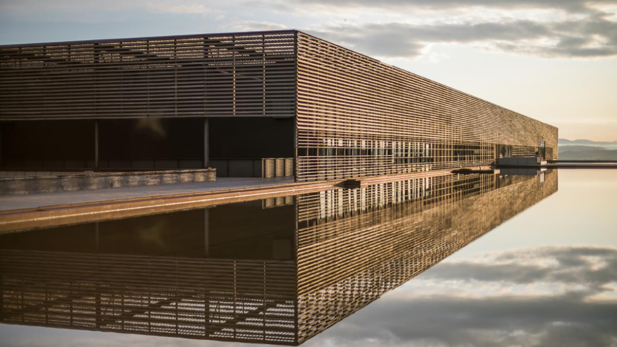 Integrada en el paisaje del Somontano, Bodega LAUS se alza como una “isla” rodeada por una lámina de agua, símbolo de su apuesta por la naturaleza y la arquitectura contemporánea.