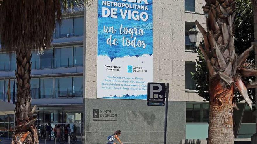 Enorme cartel en la sede de la Xunta para exaltar el &quot;compromiso cumplido&quot;  |  El edificio institucional de la Xunta en Vigo luce sobre su fachada un cartel de grandes proporciones que celebra la próxima constitución del Área Metropolitana de Vigo después de que el Parlamento Gallego aprobase la ley y el presidente Núñez Feijóo la firmase la semana pasada en un acto con presencia de los 14 alcaldes. Bajo el lema &quot;Un logro de todos&quot;, el Gobierno gallego señala que la creación del ente es un &quot;compromiso cumprido&quot;, con el logo de la administración autonómica al lado y debajo los nombres de los municipios.