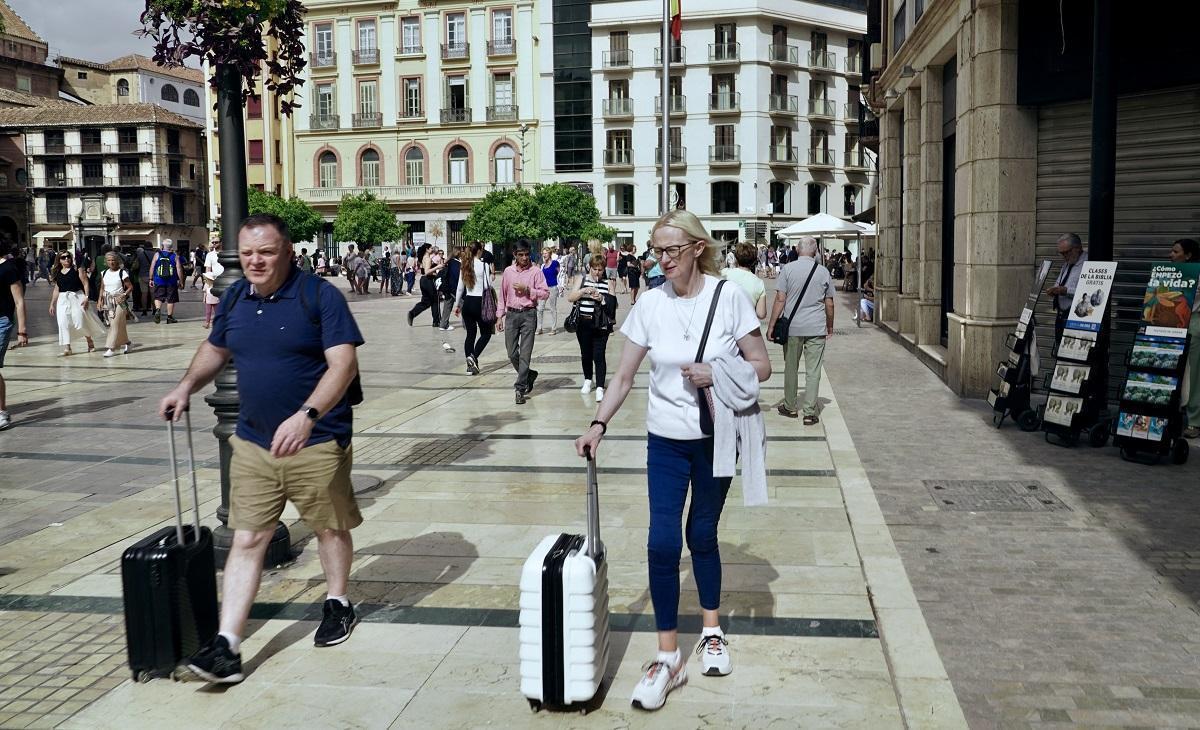 Turistas con sus maletas en la plaza de la Constitución de Málaga.