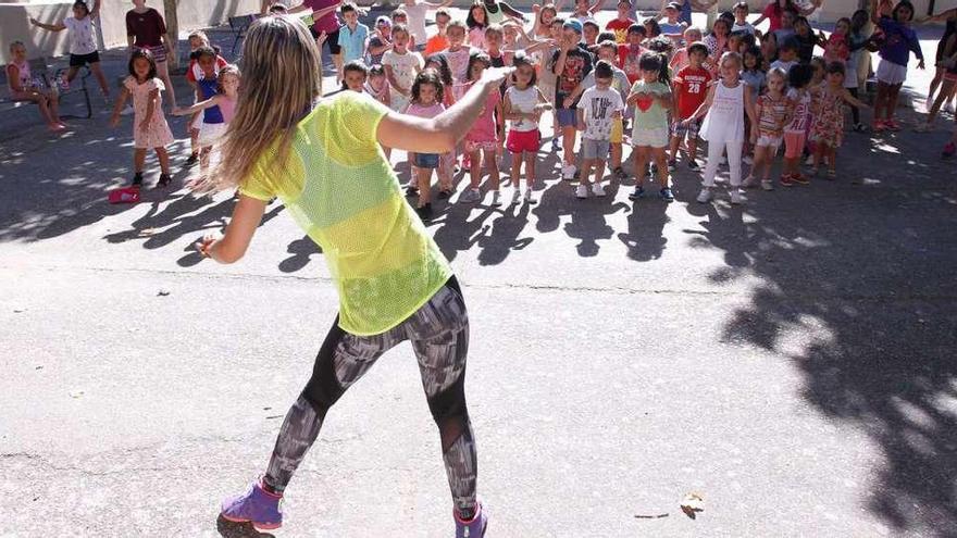 La profesora imparte la clase de zumba en el patio de las antiguas escuelas de Pinilla.