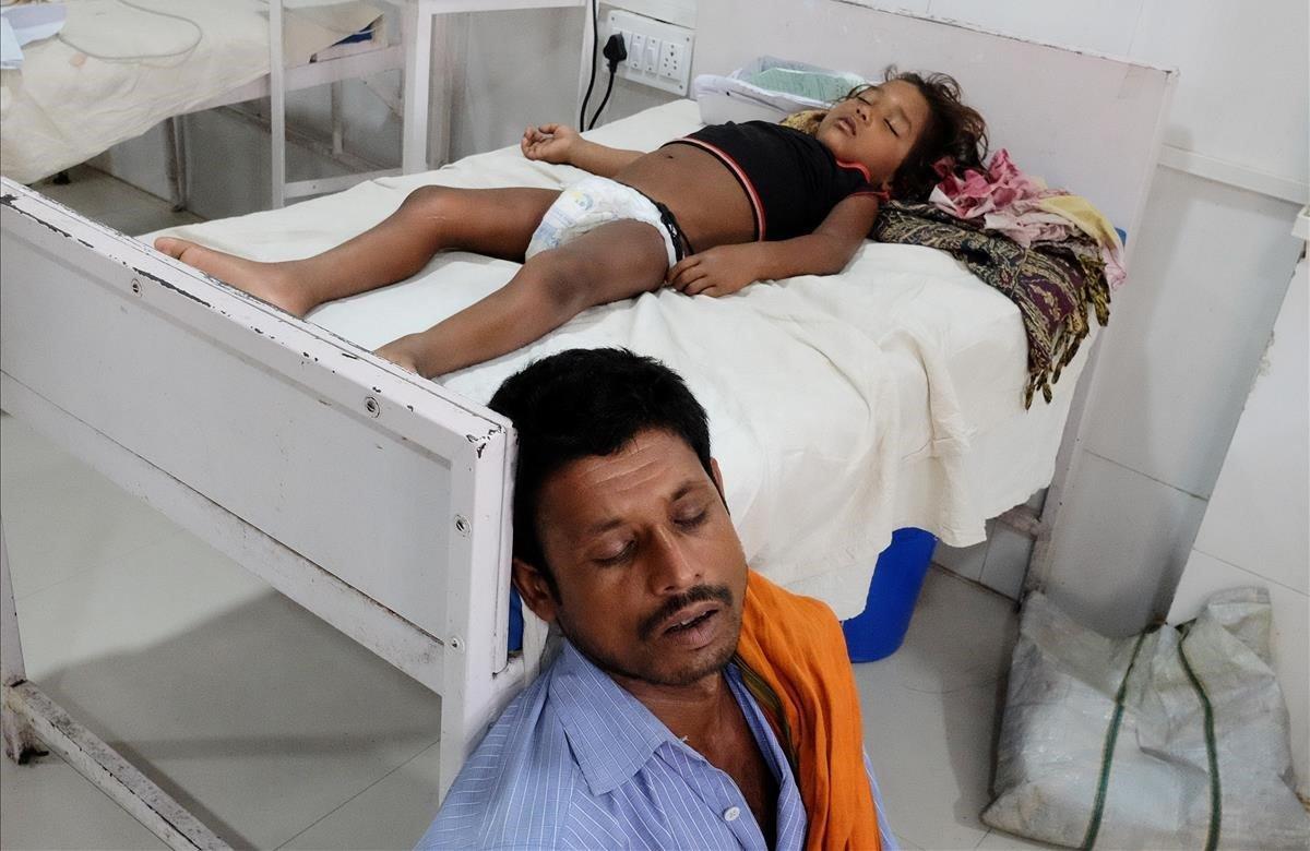 Un hombre duerme junto a su hija que sufre de síndrome de encefalitis aguda en un hospital de Muzaffarpur, en el estado oriental de Bihar, India.