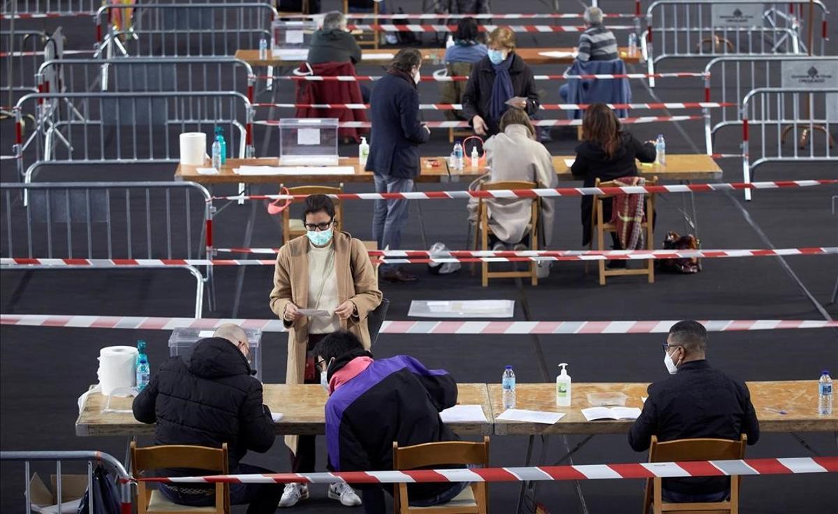 Varias personas votan en el colegio electoral del polideportivo municipal de Palau en Girona, a primera hora de este domingo.