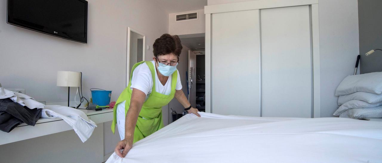 Una camarera de piso hace la cama de una habitación en un hotel.