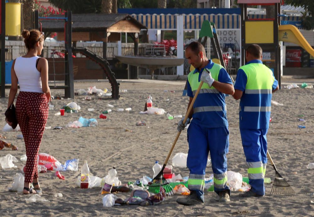 Los operarios de los servicios de limpieza trabajan para dejar la playa en óptimas condiciones tras una larga noche de fiesta en la arena