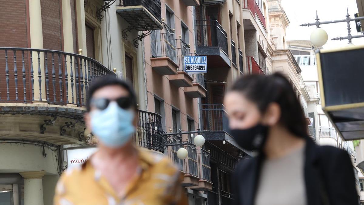 Dos mujeres pasean junto a un cartel de &quot;se alquila&quot;.