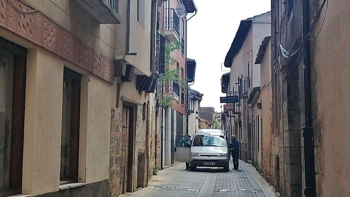 Vecinos acceden a un coche parado en la calle Barrios, único acceso desde el sudeste al casco histórico. | M. J. C.