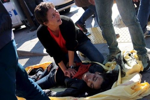 A woman helps an injured woman after an explosion during a peace march in Ankara