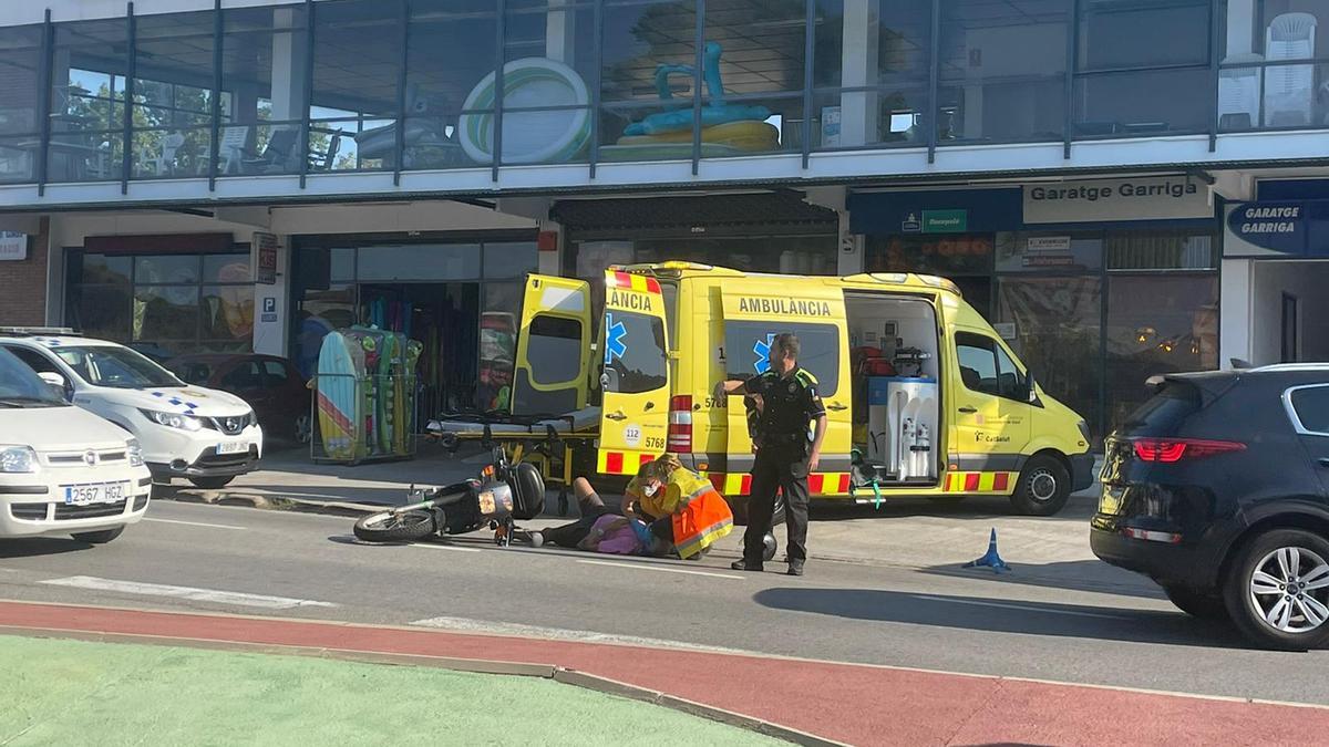El motorista a terra essent atès pel SEM a Llançà i un agent de la Policia Local.