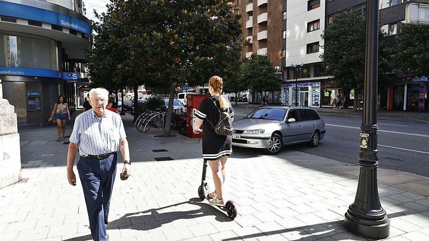 Una joven circula en patinete eléctrico por una acera de la calle Álvarez Garaya.