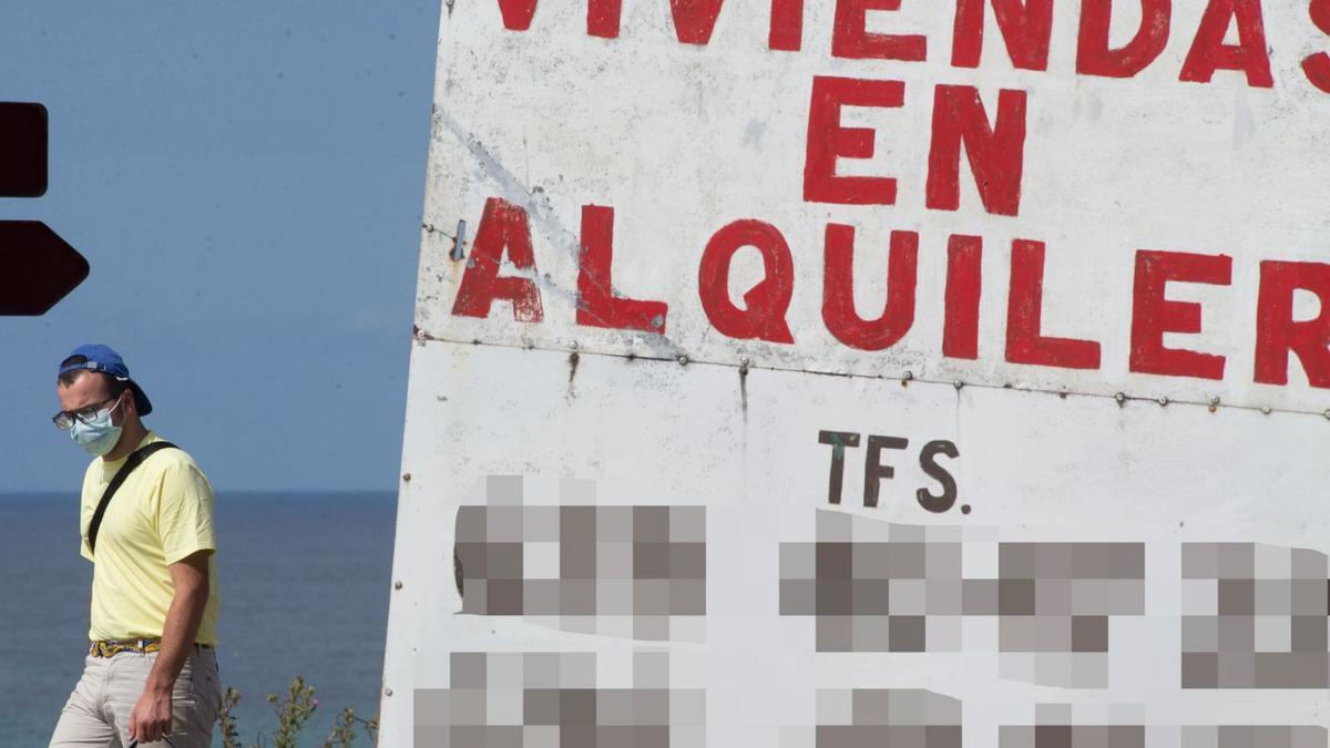 Un joven pasa frente a un anunció de viviendas en alquiler.