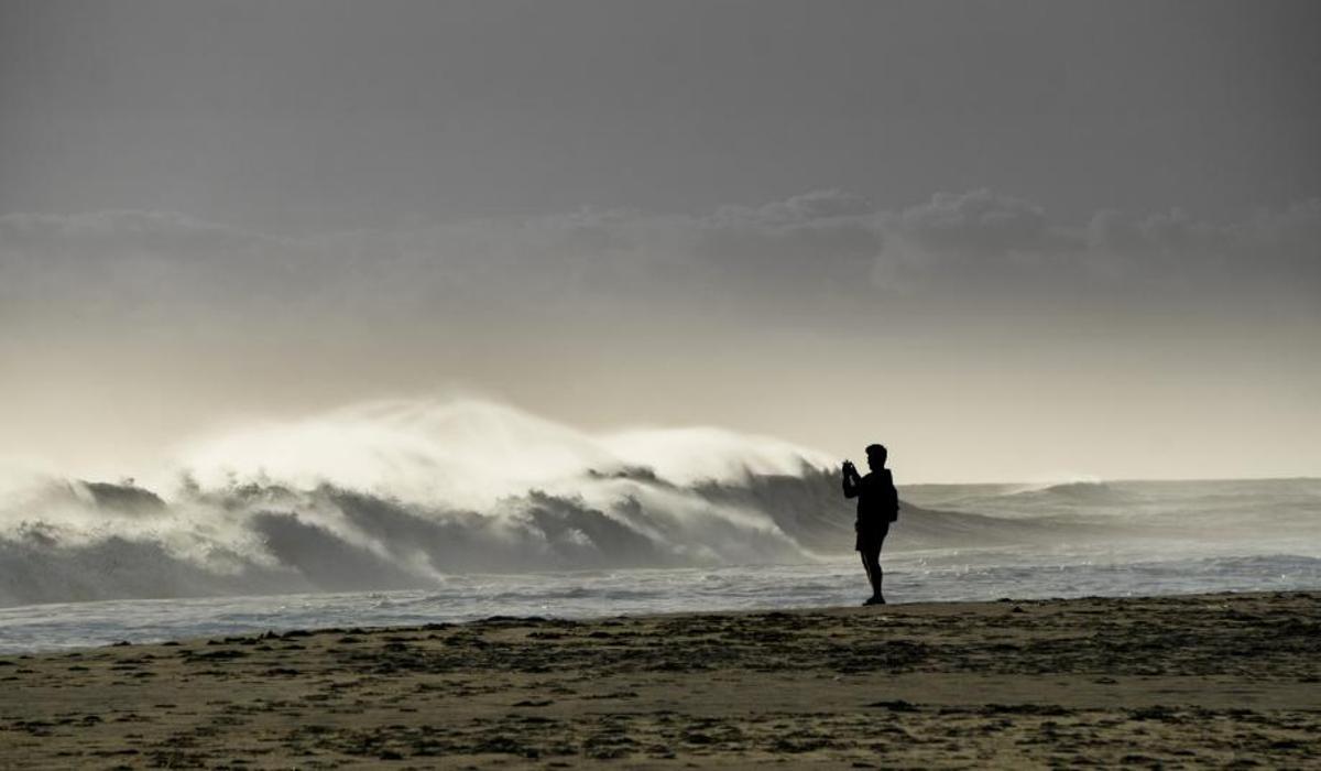 Un chico toma una fotografía del oleaje en la playa