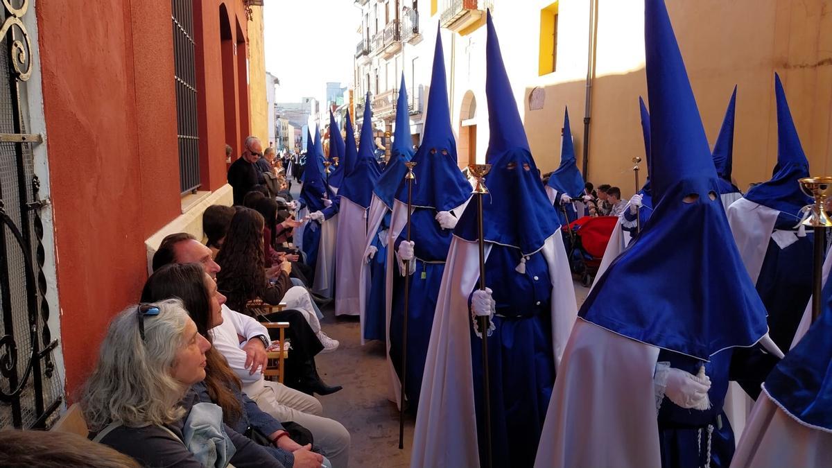 Un cofrade de la Santa Cena ofrece caramelos a los espectadores, un gesto típico de la procesión alzireña.