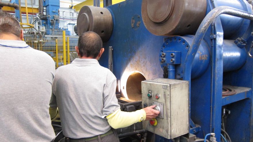 Dos hombres trabajando en una fábrica industrial.