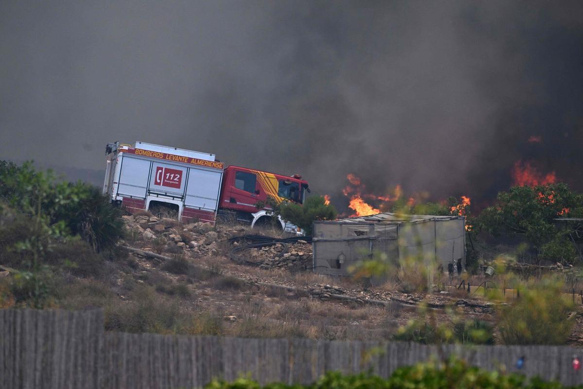 Una foto tomada el 10 de julio de 2026 muestra un camión de bomberos en una carretera junto a las llamas, cerca de un cobertizo de jardín, en el área de un incendio forestal que mató a 11 personas cerca de Bedar, en el distrito de Los Gallardos, en la provincia de Almería.
