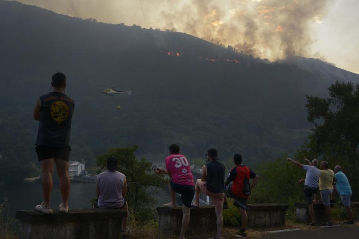 Vecinos contemplan las maniobras de extinción del incendio de Ribas de Sil, en Lugo.