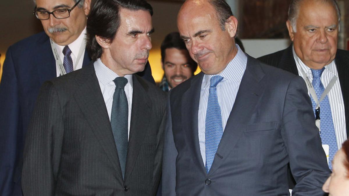 Luis de Guindos (derecha) habla con el expresidente del Gobierno José María Aznar, el jueves en Madrid, en el Foro Global de Sostenibilidad.