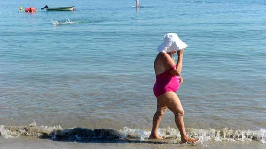 Una mujer pasea por la playa de Santa Cristina.