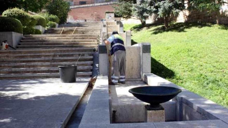 Un operario de limpieza trabaja junto a una de las cascadas inactivas en un parque de la Zona Norte.