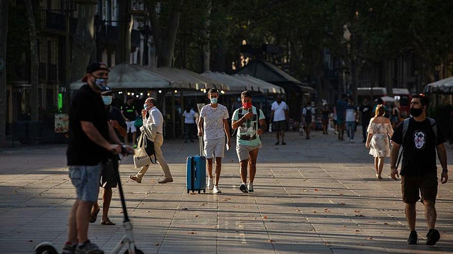 Un turista camina amb la maleta per la Rambla de Barcelona.