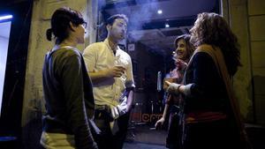 Un grupo de personas fumando en el exterior de un bar de la calle Vallfogona del barrio de Gracia.