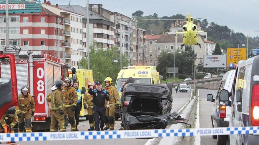 El automóvil, volcado en la mediana, entre agentes de Policía Local y Bomberos de Ourense. // Iñaki Osorio